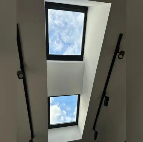 Two skylights in a ceiling with black frames.
